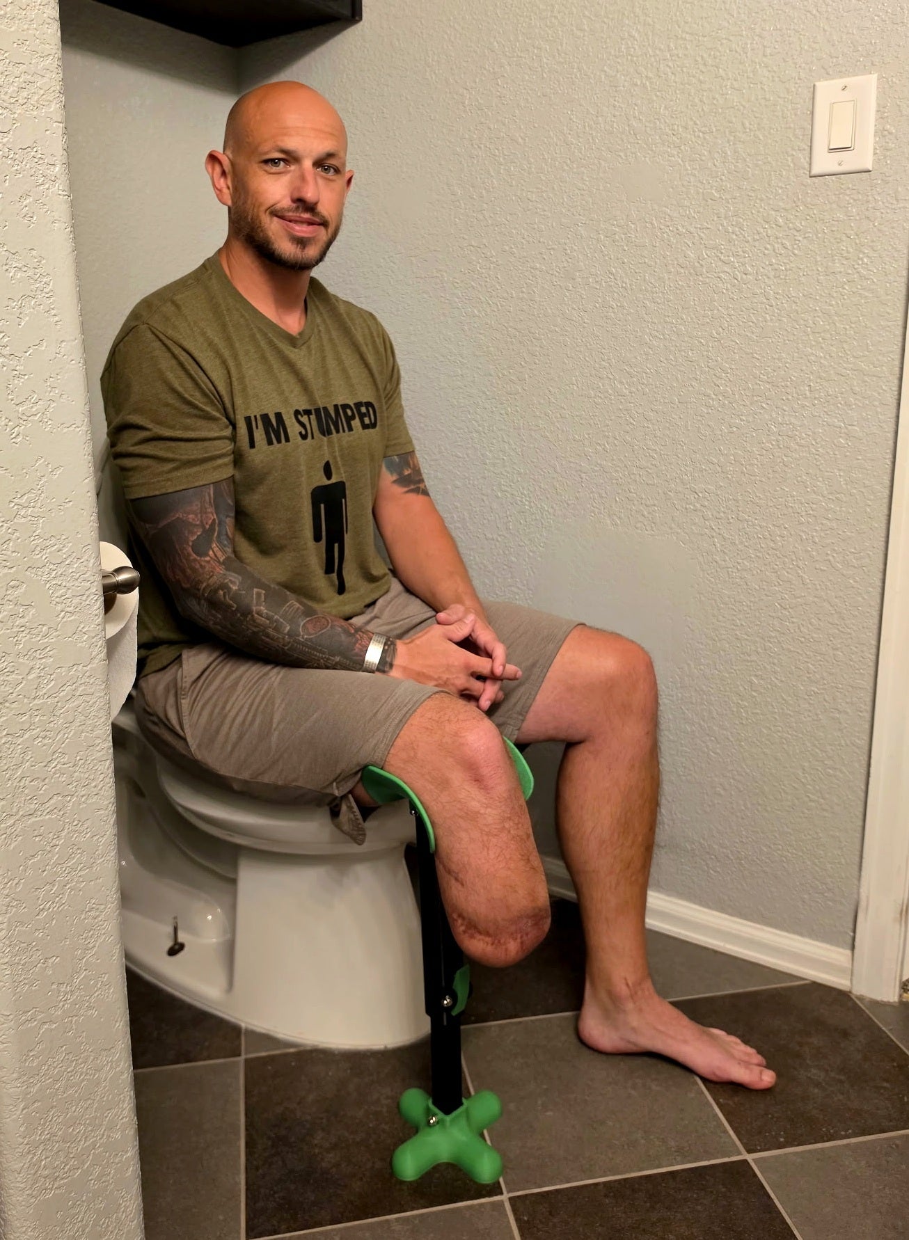 Andrew Hall, US Army veteran and inventor of the AmpuTIEase Leg Rest, using it to support his residual limb while seated in the restroom